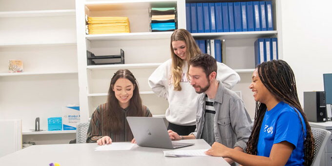 Students talking to each other and looking on a computer